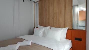 A modern hotel room with a large bed, wooden headboard, and a mirror reflecting the room.