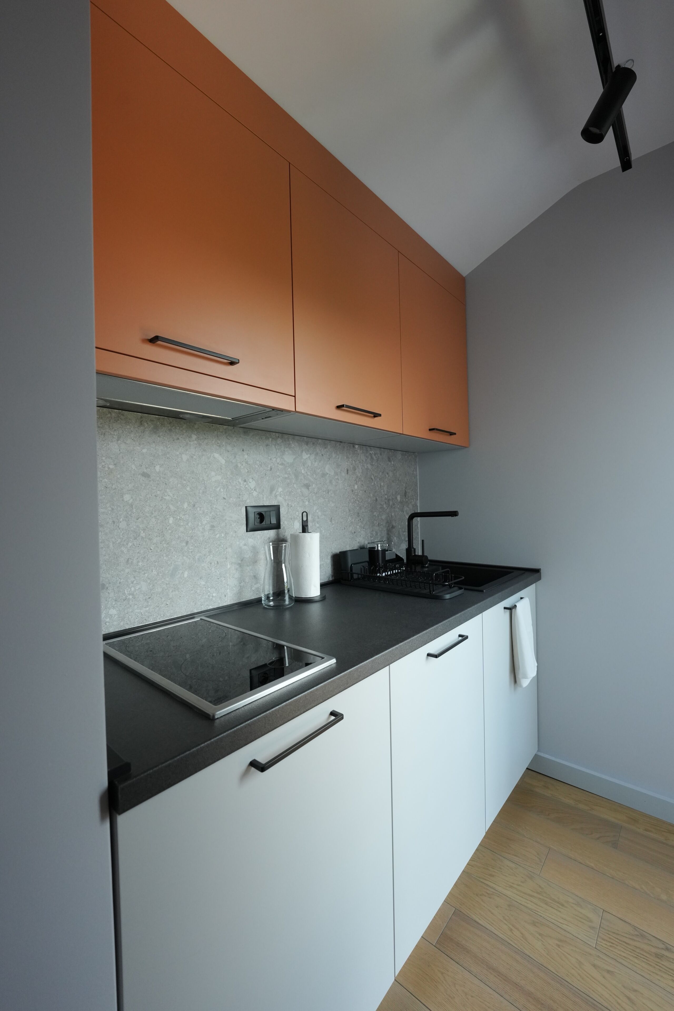 A modern kitchen with a granite countertop, a built-in stove, and white cabinets.