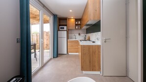 Een kleine keuken met houten kastjes, een magnetron en een spoelbak.