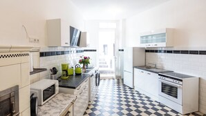 A modern kitchen with white cabinets, a black and white checkered floor, a microwave, a coffee maker, and a sink.
