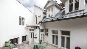 A courtyard with a stone floor, a table with chairs, and potted plants.