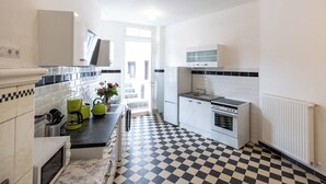 A modern kitchen with white cabinets, a black and white checkered floor, a built-in oven, and a window providing natural light.