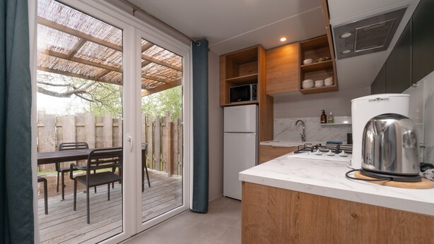 A kitchen with a refrigerator, microwave, and coffee maker. - Mobile Home "Au vert du jardin" 500m from the Beach (Plouhinec)