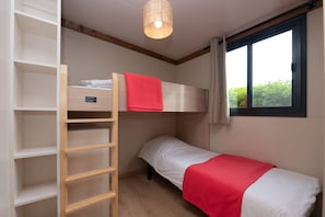 Een stapelbed met een rode deken, een houten trapje en een raam met gordijnen.