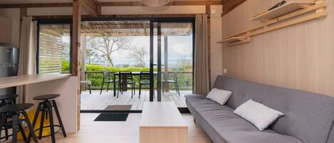 Una sala de estar moderna con un sofá, una mesa de centro y un comedor con taburetes.
