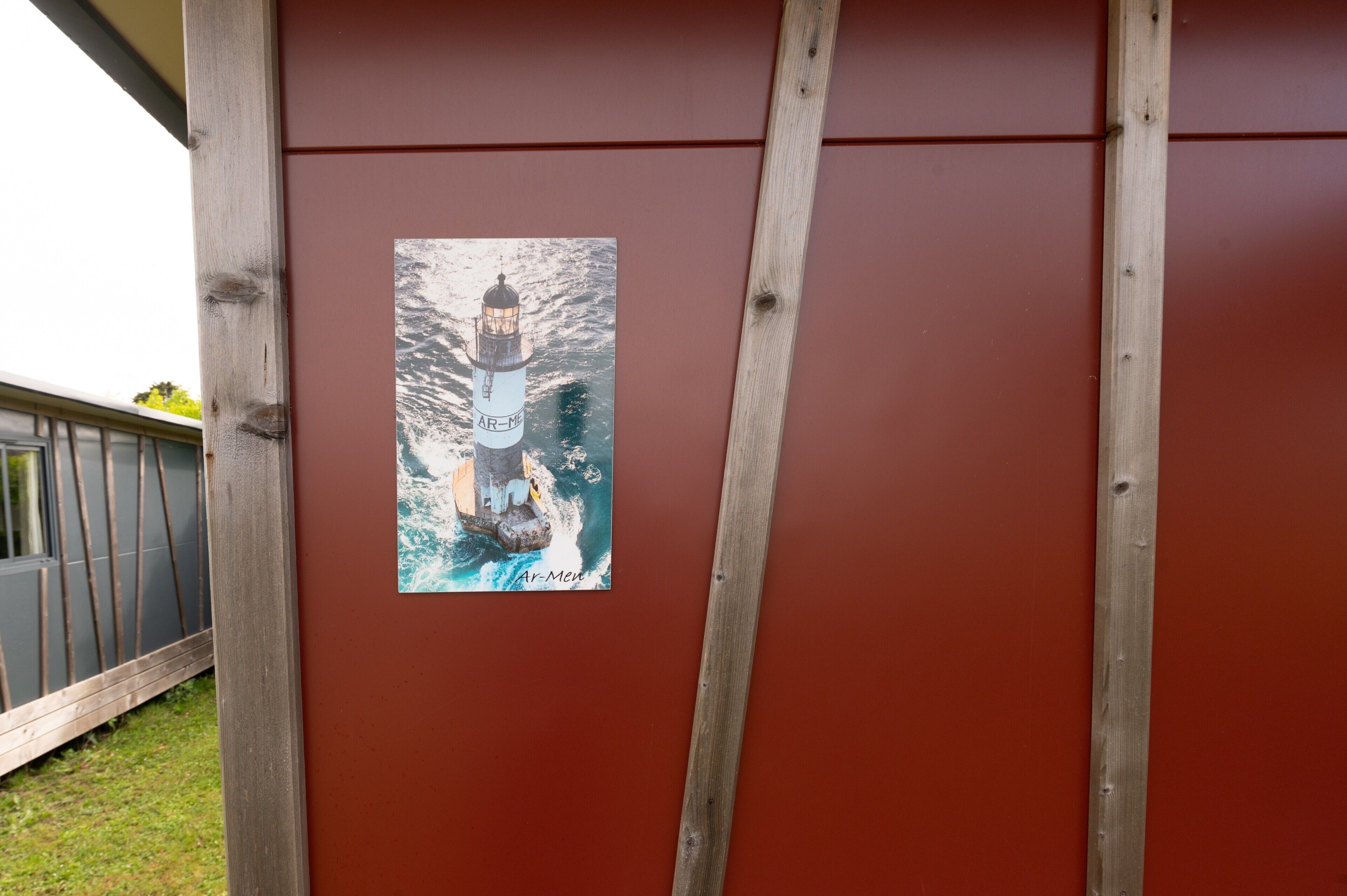 A wooden structure with a red wall and a framed picture of a lighthouse.