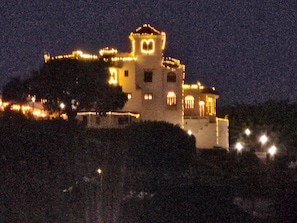 A large, illuminated building with multiple levels and a prominent tower, surrounded by trees. - Ponce Pueblo Apartment (Ponce)