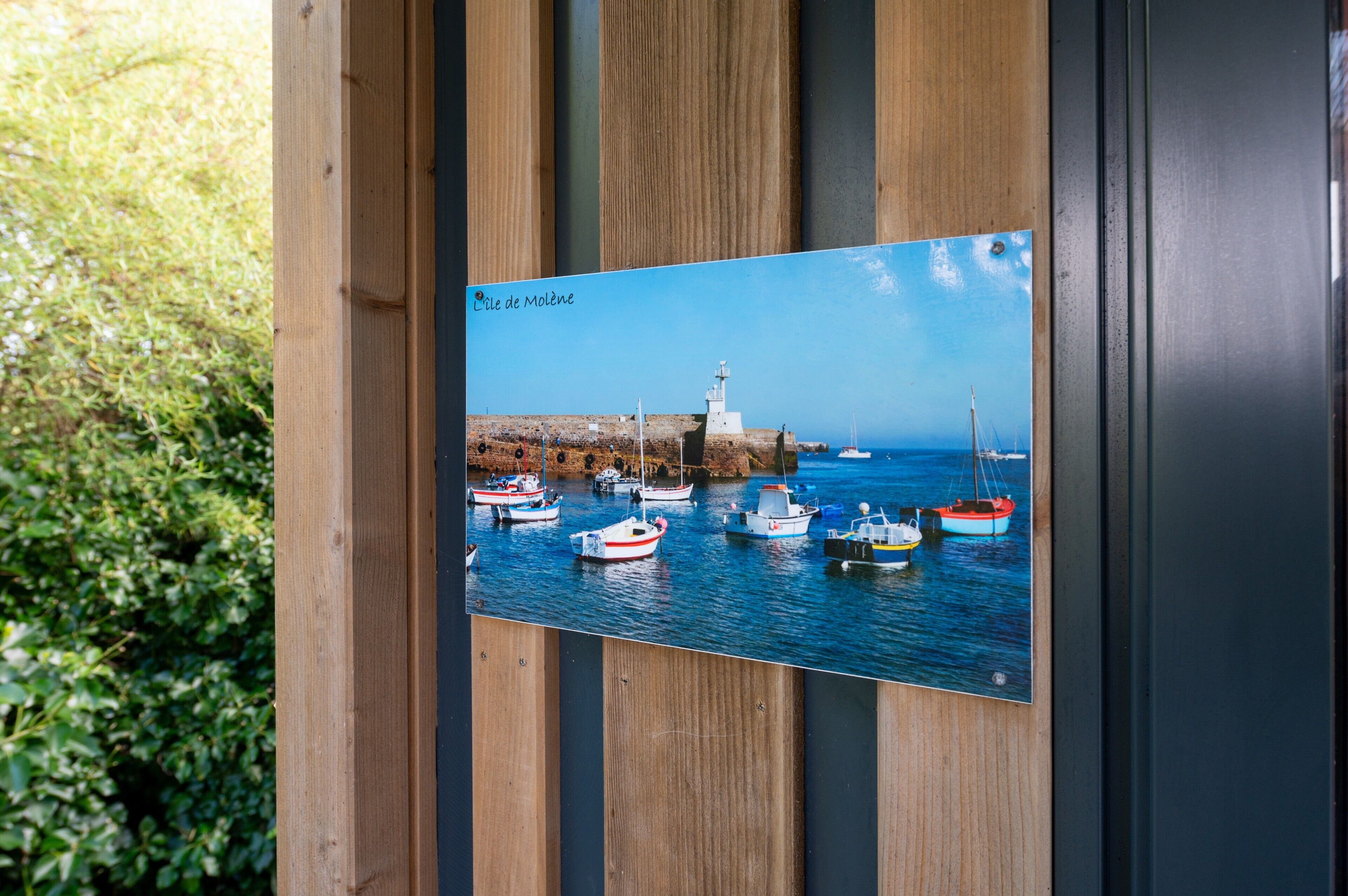 A photograph of a coastal scene with boats and a lighthouse, mounted on a wooden structure.