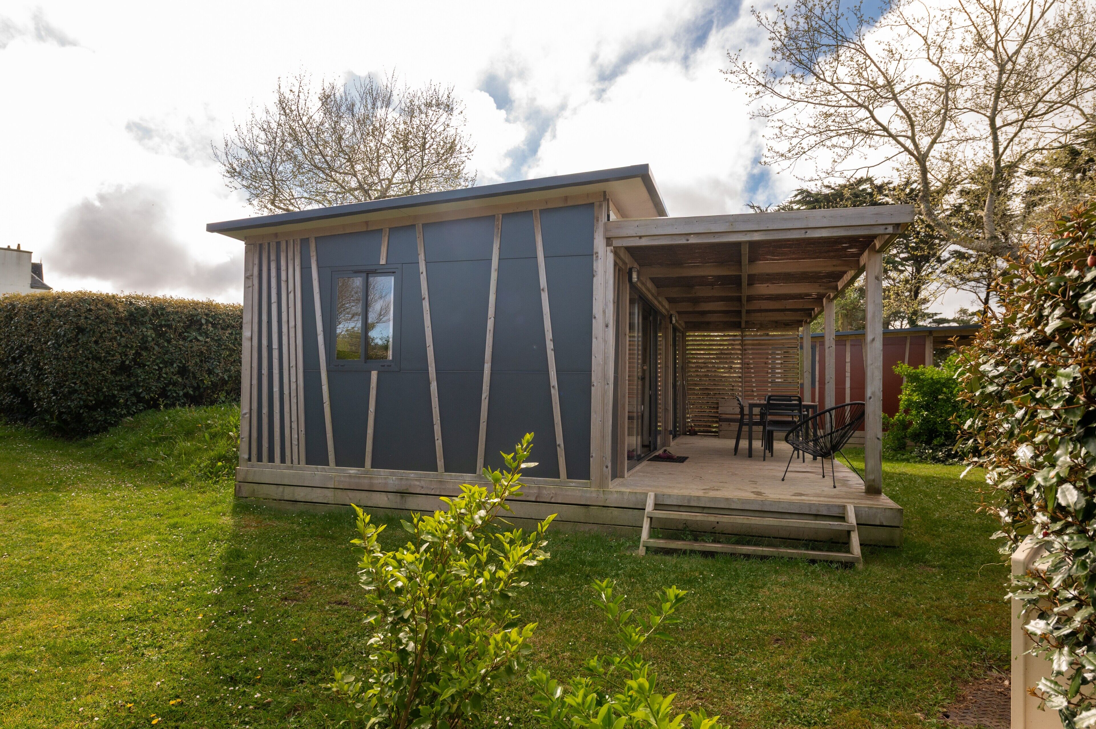A small, modern cabin with a covered porch and a patio area.