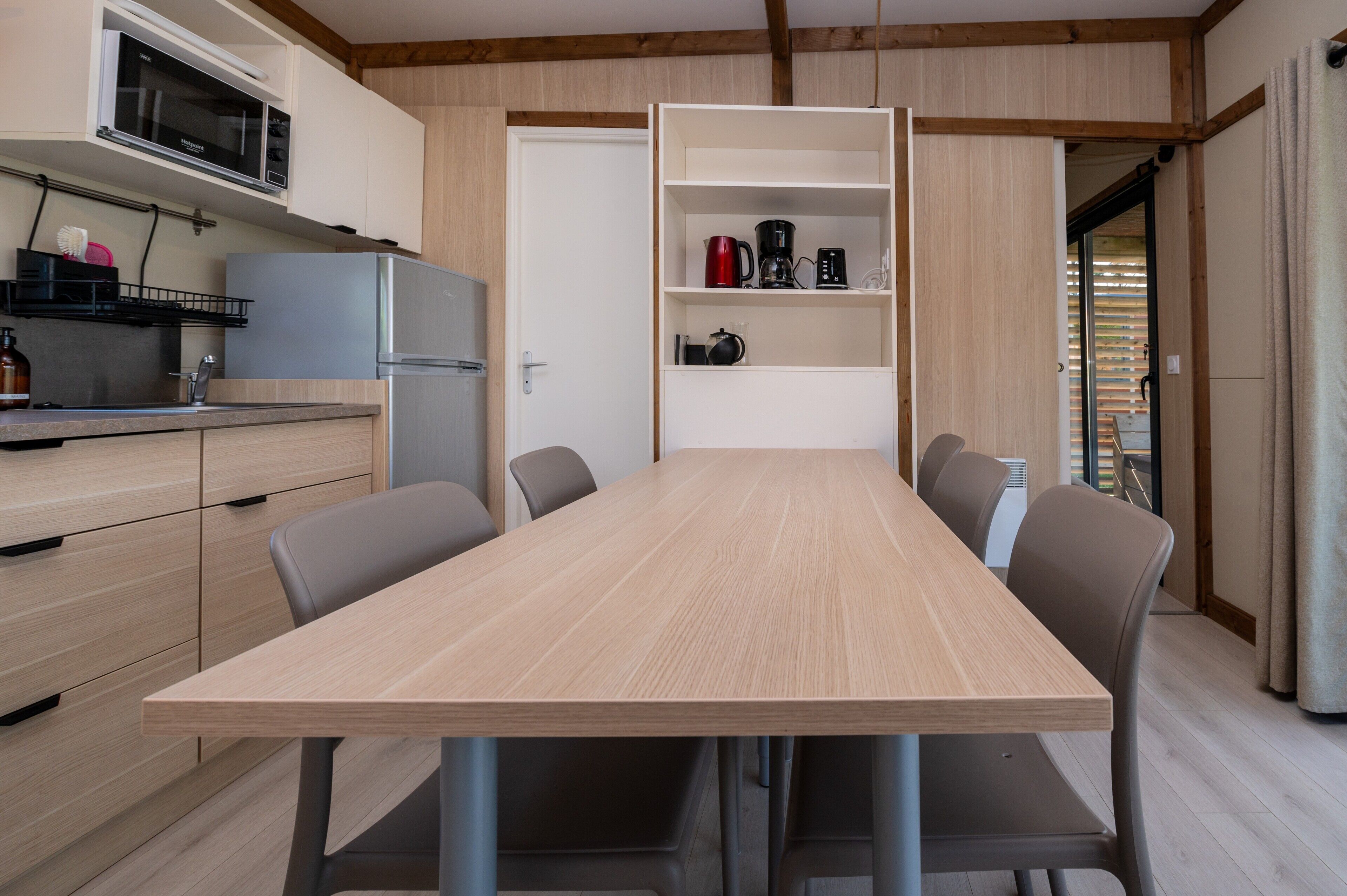 A compact kitchen with a microwave, refrigerator, and open shelving with kitchenware.