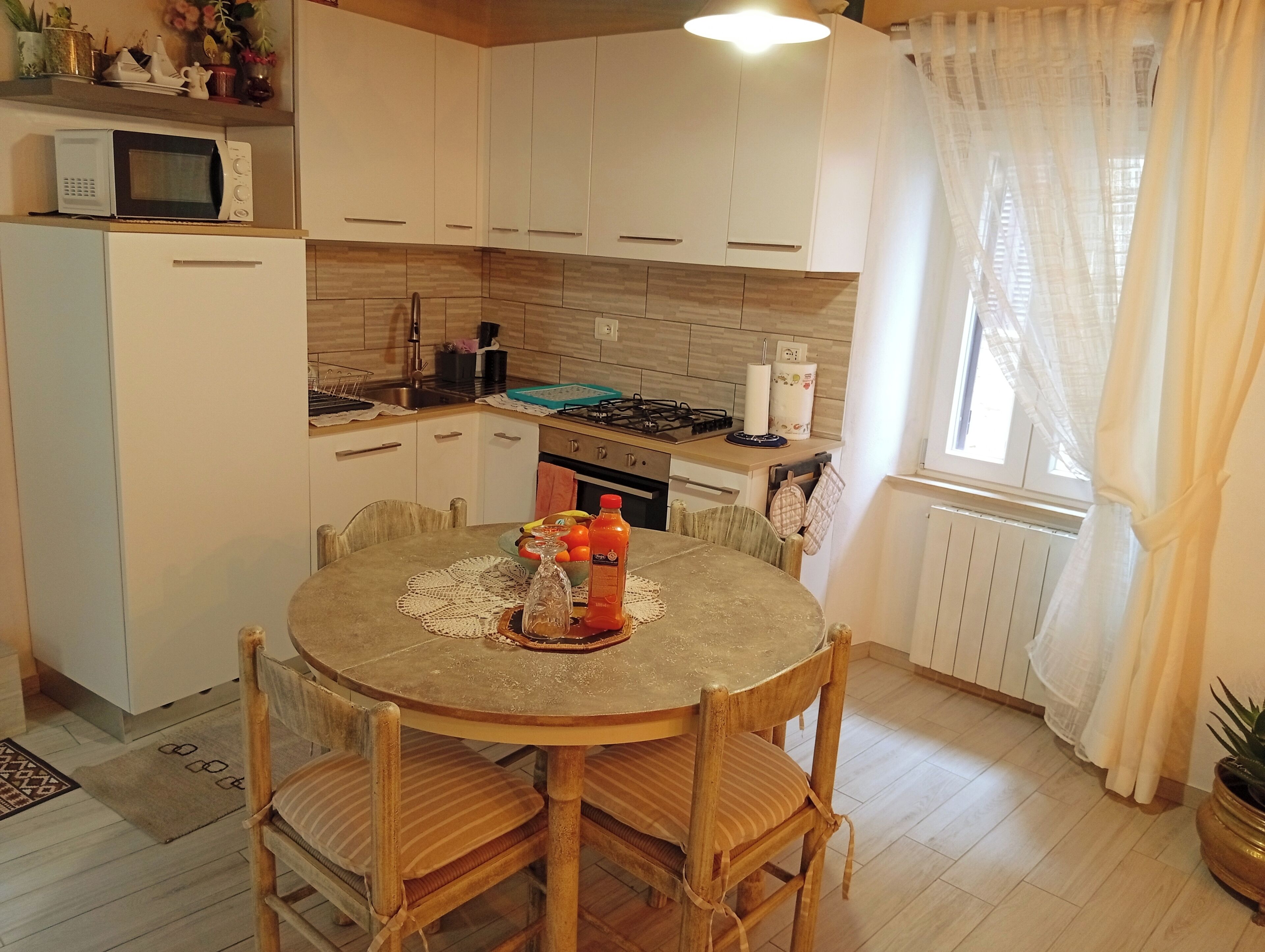 Une cuisine compacte avec des meubles blancs, un four à micro-ondes, une cuisinière et une table à manger avec des chaises.