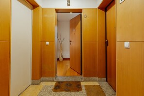 A hallway with wooden doors, a doormat, and a vase with branches. - DOWNTOWN DELUXE 3 by VACATIONY (Oporto)