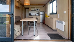 Een compacte keuken met moderne apparaten, een eethoek met een tafel en stoelen, en een groot raam dat voor natuurlijk licht zorgt.