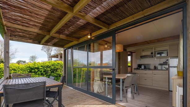 Een open leefruimte met een eettafel en stoelen, een keuken met moderne apparatuur en uitzicht op de omgeving.