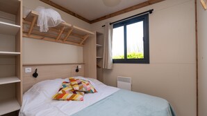 Een slaapkamer met een bed, raam, radiator en inbouwkasten.