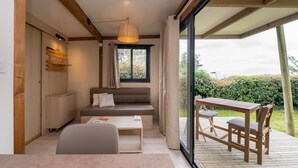 A modern room with a sofa, a table, and a dining area. - Chalet “20m² - Les Îles Vierges” with Terrace (Plouhinec)