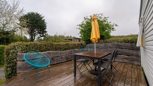 Une terrasse en bois avec une table et des chaises, un parasol jaune et une clôture en bois.