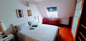 A bedroom with a bed, a nightstand, a dresser, a window, and wall-mounted artwork. - Room "A Splendid Room in Wonderful Rome" with Private Terrace, Wi-Fi, and Air Conditioning (Roma)