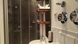 Un baño moderno con ducha de vidrio, lavamanos blanco y tocador de madera.