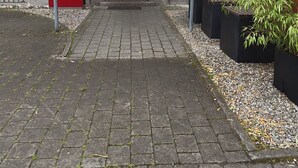 Entrada de un edificio con puerta de madera, toldo rojo y un letrero que indica zona residencial.