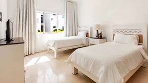 Een hotelkamer met twee bedden, een bureau, een lamp en een televisie.