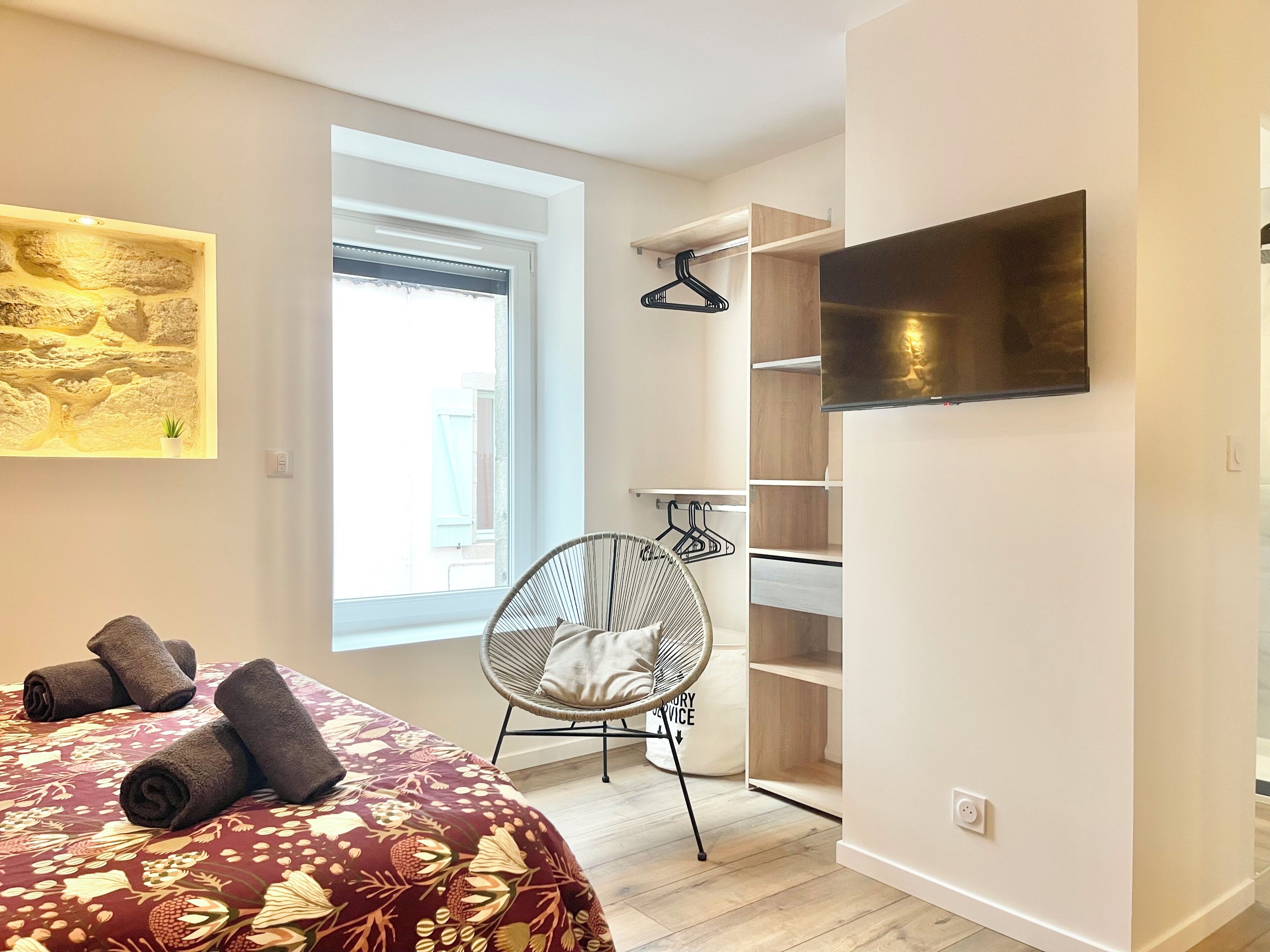 Une chambre à coucher avec un lit, une chaise, une armoire et un téléviseur.