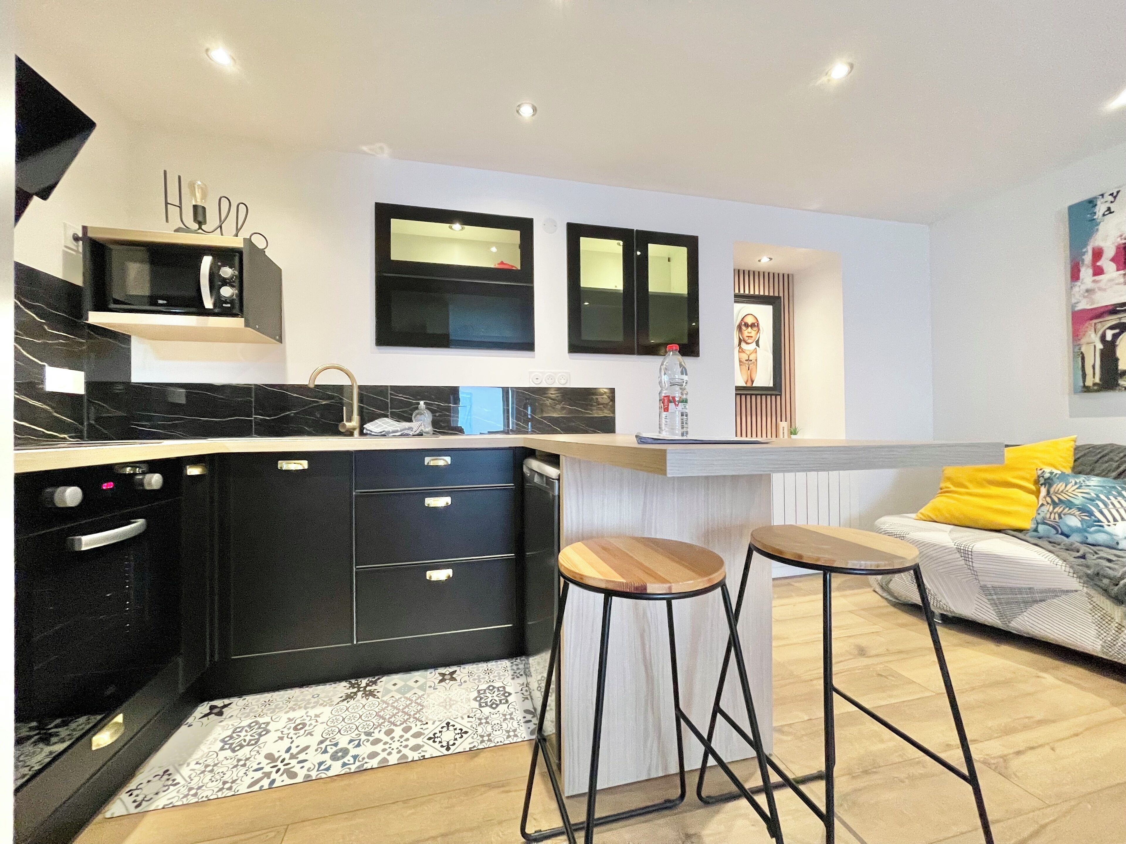 A modern kitchen with black cabinetry, a built-in microwave, and a large island with stools.