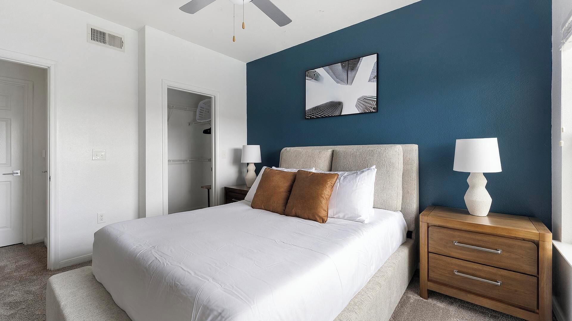 A bedroom with a bed, nightstands, a ceiling fan, and a wall-mounted picture.
