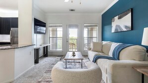 A modern living room with a sofa, a coffee table, and a TV mounted on the wall. - Landing | Beautiful 1BD, Gym, Courtyard (Austin)