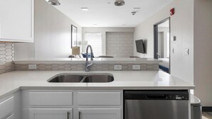 A modern kitchen with white cabinetry, a double sink, and a dishwasher. - Landing | Chic 1BD, Game Room, Courtyard (Birmingham)