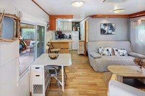 A compact living space with a kitchenette, dining area, and a sofa with patterned cushions.