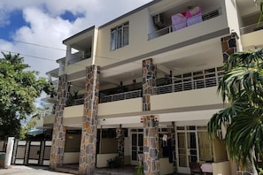 A multi-story residential building with a central courtyard, stone pillars, and balconies. - Pereybere Beach Apartments: Superior Apartment (Pereybere)