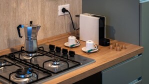 A kitchen with a gas stove, a coffee maker, a kettle, and a coffee machine. - Achille 2BR/2BA • Cozy Stay Near Venice (Venezia)