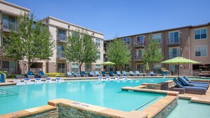 A swimming pool with lounge chairs and a stone wall. - Landing | Incredible 2BD, Clubhouse, Pool (Dallas)