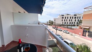 Un balcón con vistas a una calle, una piscina y edificios.