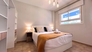 Un dormitorio con cama, lámparas de noche, ventana y armario.