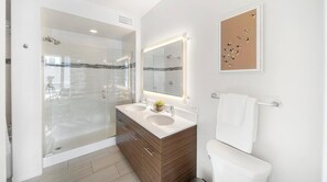 Een moderne badkamer met een douchecabine van glas, een wastafel met twee kommen en een toilet.