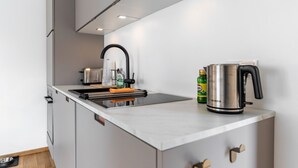 Une cuisine moderne avec une bouilloire en acier inoxydable, une bouteille contenant un liquide vert et un grille-pain.