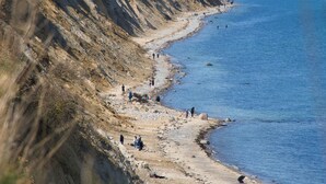 Un paysage côtier avec une plage de sable, des falaises et un ciel dégagé.