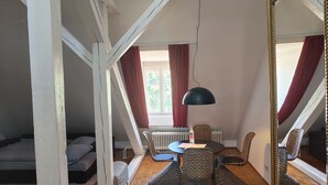 Um quarto no estilo loft com teto inclinado, uma cama, uma mesa de jantar com cadeiras e um espelho grande.