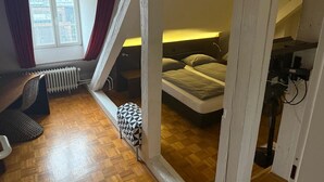 Quarto pequeno com uma cama, uma escrivaninha e um radiador.