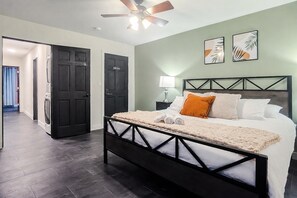 Un dormitorio con cama, ventilador de techo y mesita de noche con lámpara.