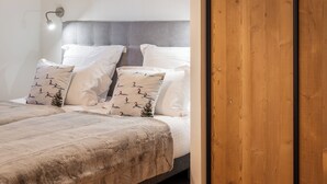 Una camera da letto con un letto, un armadio in legno, una lampada a sospensione e un comodino con lampada.