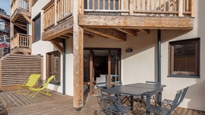 Un terrazzo in legno con tavolo e sedie, una sedia gialla e un balcone in legno.