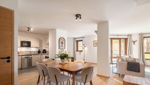 Una cucina moderna con elettrodomestici in acciaio inossidabile, un tavolo da pranzo in legno con quattro sedie e una pianta in vaso.