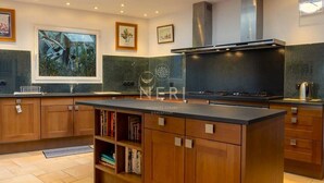 A modern kitchen with wooden cabinets, a central island, and a backsplash with green tiles.