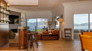 A spacious living area with a large window overlooking a scenic view, a wooden bar area, and a cozy seating arrangement. - Villa AMBRA - 6 bedrooms, panoramic sea view, swimming pool (ALBITRECCIA)