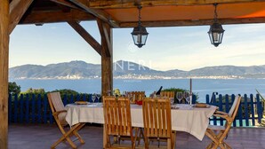 An outdoor dining area with a table set for four, overlooking a coastal view with mountains in the distance. - Villa AMBRA - 6 bedrooms, panoramic sea view, swimming pool (ALBITRECCIA)