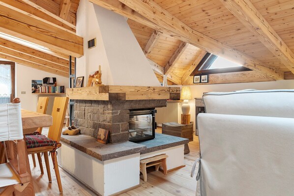 A cozy attic room with a stone fireplace, wooden beams, and a skylight.