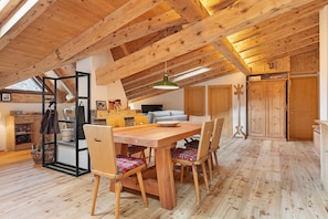 A wooden interior with a dining table, chairs, and a ceiling with exposed beams.